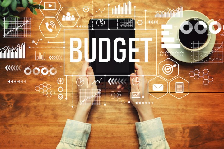 the word budget alongside charts and graphs over a person holding a device