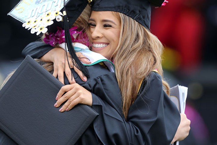 Graduates in caps and gowns hugging