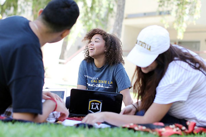 Three students sitting on lawn