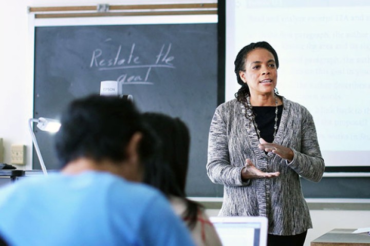 Professor teaching room of students in front of blackboard