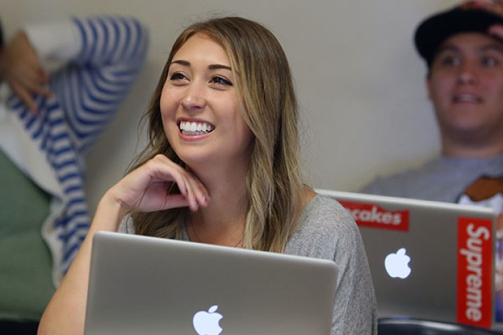 student with laptop smiling in classroom