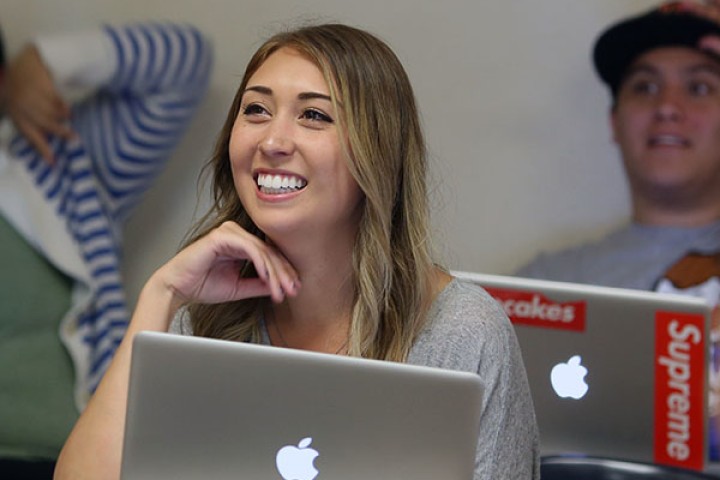  student with laptop smiling in classroom