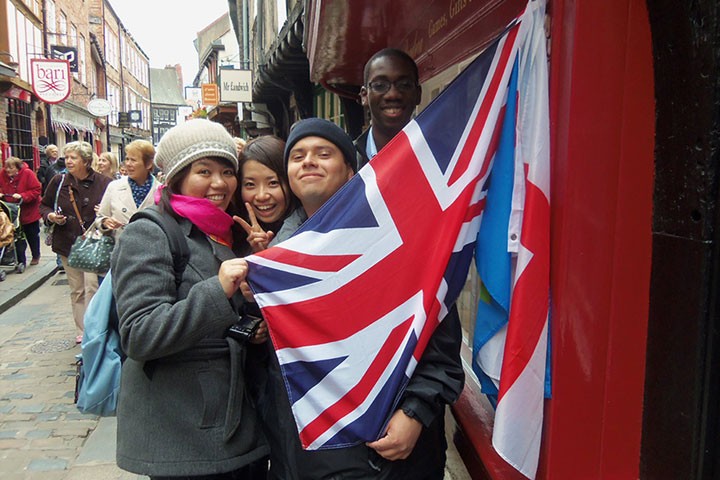 Three students holding a UK flag