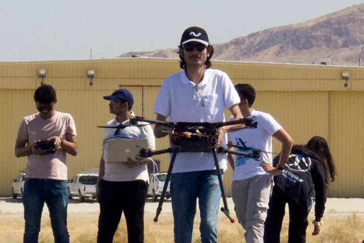 student holds UAV during competition in desert with mountain behind