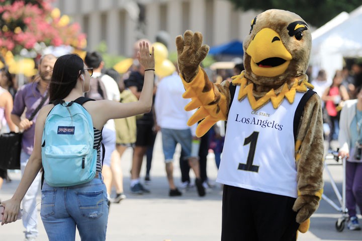 Eddie the Eagle high-fives a student.