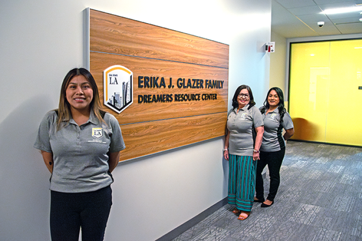 Three people standing by the wall sign for the Glazer Family Dreamers Resource Center.