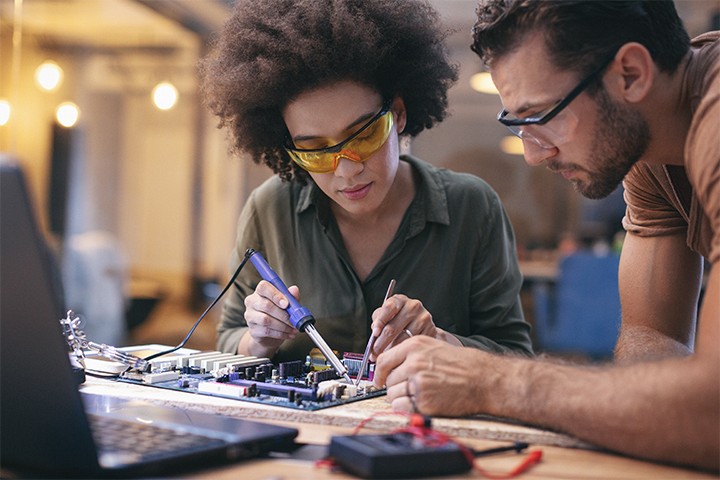 Female and male electrical engineers working on circuit board