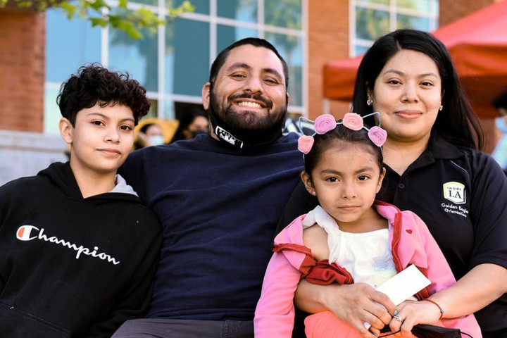 Two parents sit with their two small children. The parents are smiling.