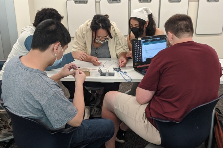 students collectively working on electrical component and computer