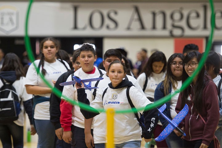 young girl throws airplane through hoop