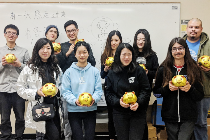 Group of students holding gold item in a classroom