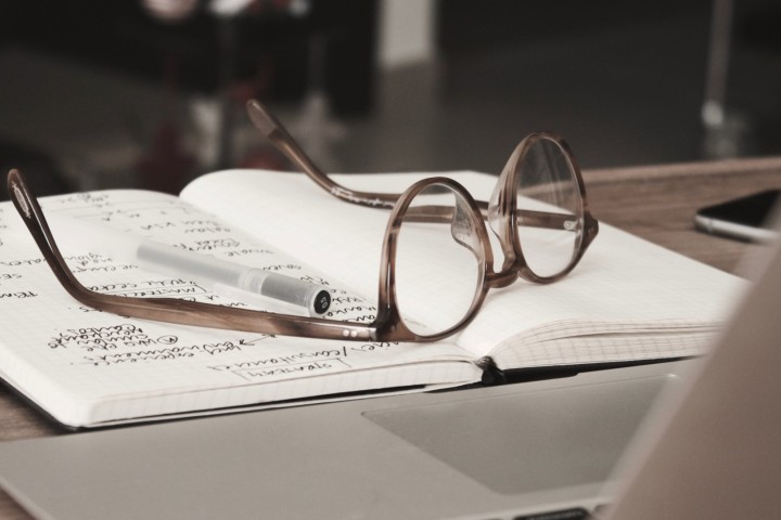 notebook with glasses resting on top