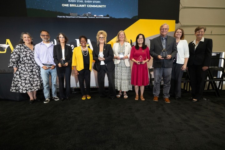 Cal State LA faculty and administrators pose with award recipients holding plaques during a university recognition ceremony. 