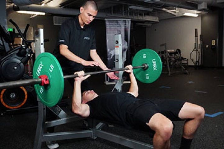 Person weightlifting on a bench with a spotter.