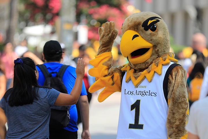 Eddie the Eagle high fives student on walkway