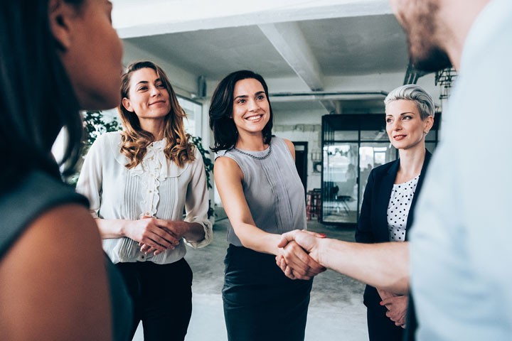 A person shaking another person's hand in a group of five