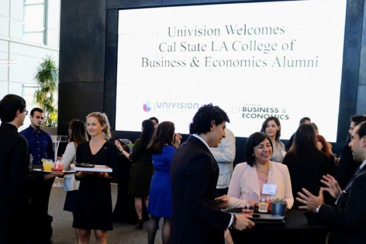 People networking around cocktail tables with Univision welcome sign