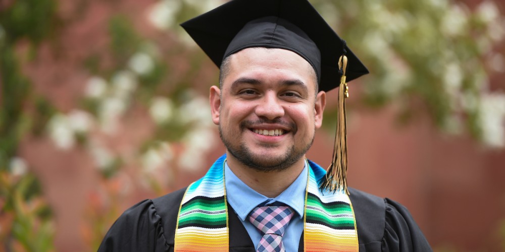 Male graduate wearing black cap and gown.