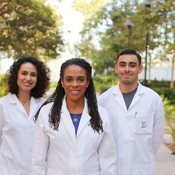 Students with White Lab Coats standing next to Dr. Foster in a courtyard