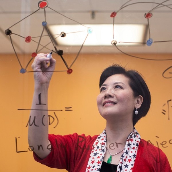 Female faculty member writing math calculations on a glass screen 