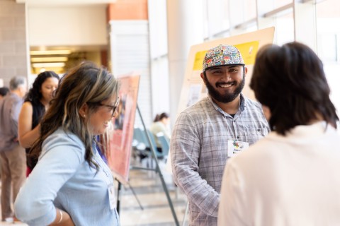 Image show three people at a LSAMP poster session talking 