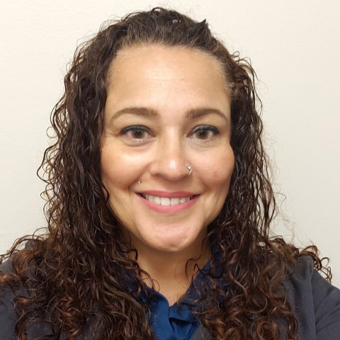 A person with long, curly hair smiling.