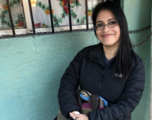 Karla sitting in a chair smiling next to an aqua wall