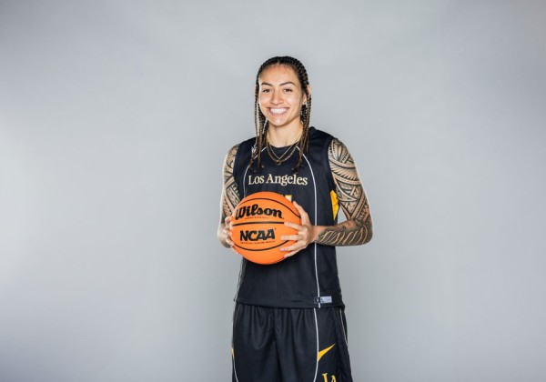 Cal State LA women’s basketball player poses in uniform holding an NCAA basketball against a neutral background.