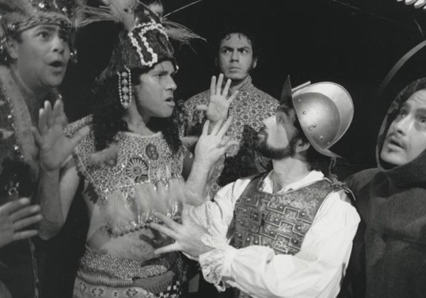 Black-and-white photo of a theatrical scene with five actors in elaborate costumes, portraying a dramatic moment in what appears to be a historical or cultural performance.