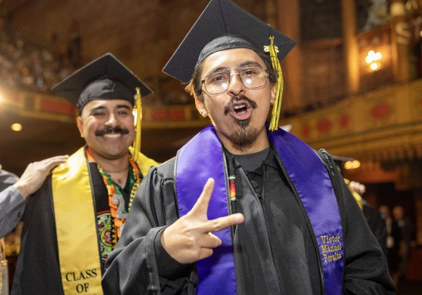 Two students at a graduation ceremony celebrating.