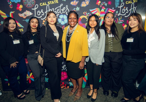 Cal State LA President stands with students in front of colorful Los Angeles backdrop at campus leadership event.