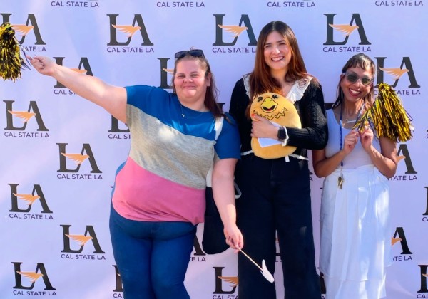 3 people stand in front of a backdrop and take a group photo.