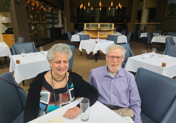 Two donors smile while seated together at a table inside a restaurant.