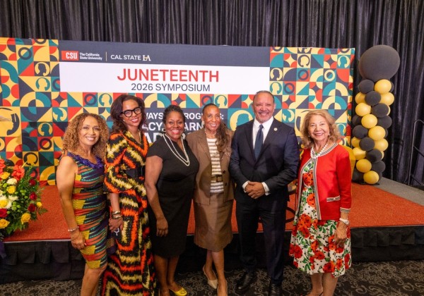 Attendees pose together in front of a Juneteenth 2026 Symposium backdrop during an event at Cal State LA.