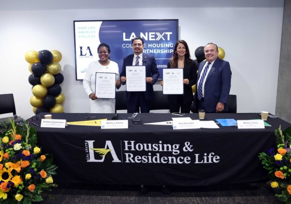 Four individuals hold signed partnership documents during the LA Next College Housing Partnership ceremony at Cal State LA. 