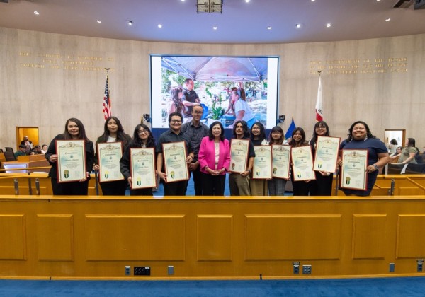 Cal State LA students and faculty hold commendation certificates in a marble hallway at the LA County building following the award ceremony.