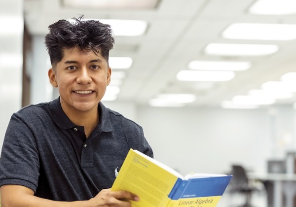 Yak de Padua wearing a black button up shirt reading a book