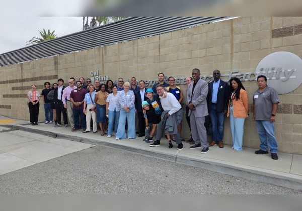Group photo of Move LA visitors gathered outside the Cal State LA Hydrogen Research Facility, posing in front of the facility sign.