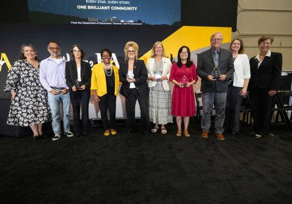 Cal State LA faculty and administrators pose with award recipients holding plaques during a university recognition ceremony. 