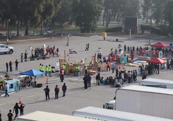 Students gather in a campus parking lot for an outdoor event featuring booths, activities, and demonstrations at Cal State LA. 