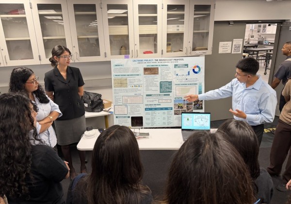 Student presents a research poster to a group of attendees during an academic research event at Cal State LA.