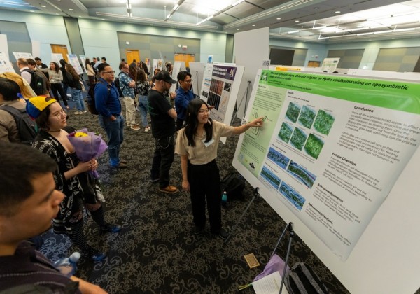 Student presents a scientific research poster to attendees during a student research poster session at Cal State LA.