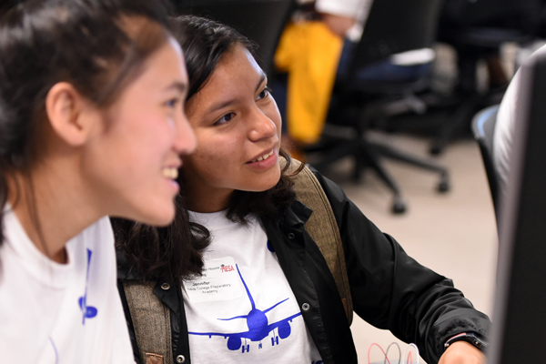 two girls smile at computer as they work