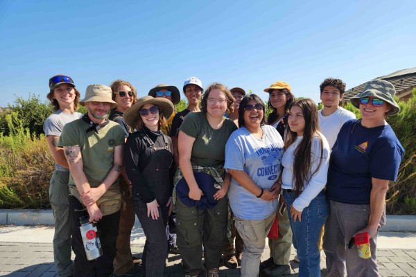 Group of students posing on a sunny day with coastline in background