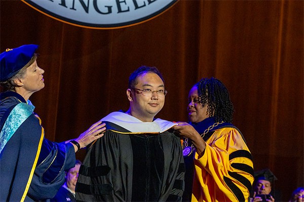 Kevin Xu being hooded by Provost Lattimer and President Eanes