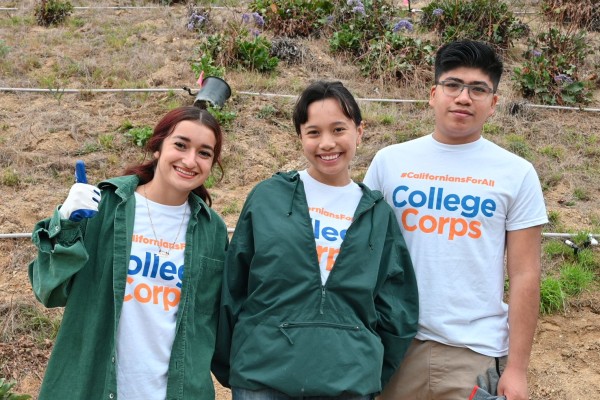 Three fellows posing in front of hill 