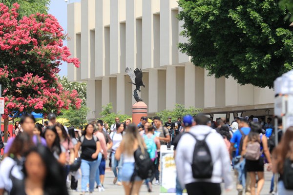 A walkway full of students with an eagle statue visible in the distance.