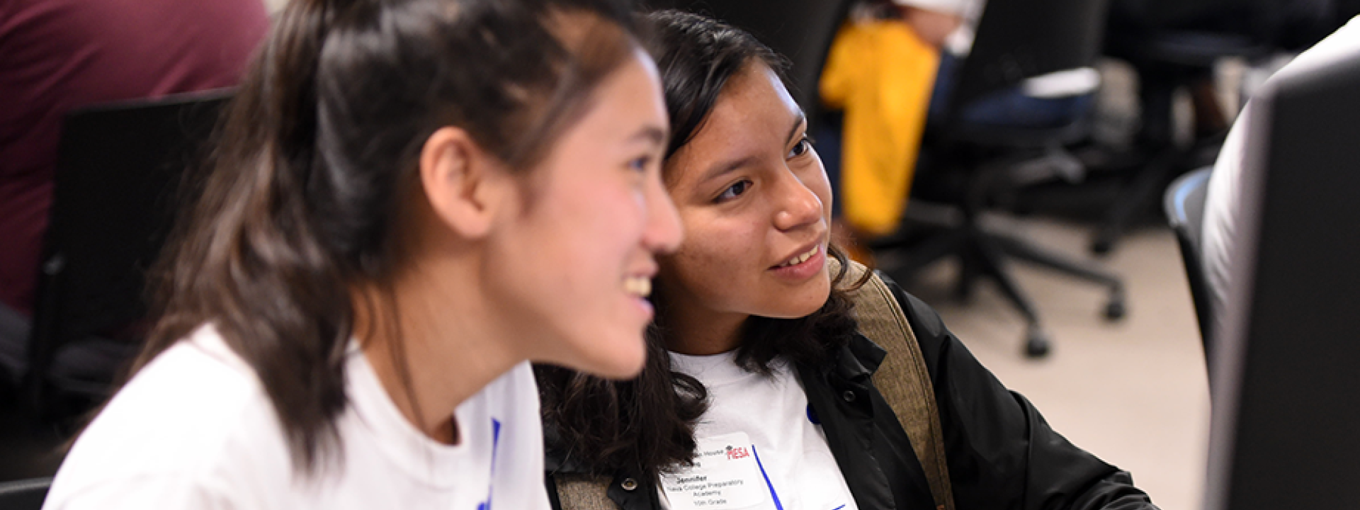 two girls smile at computer as they work