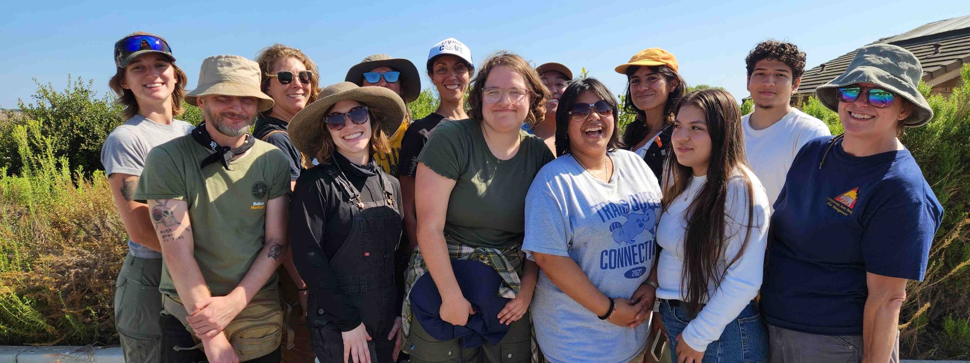 Group of students posing on a sunny day with coastline in background