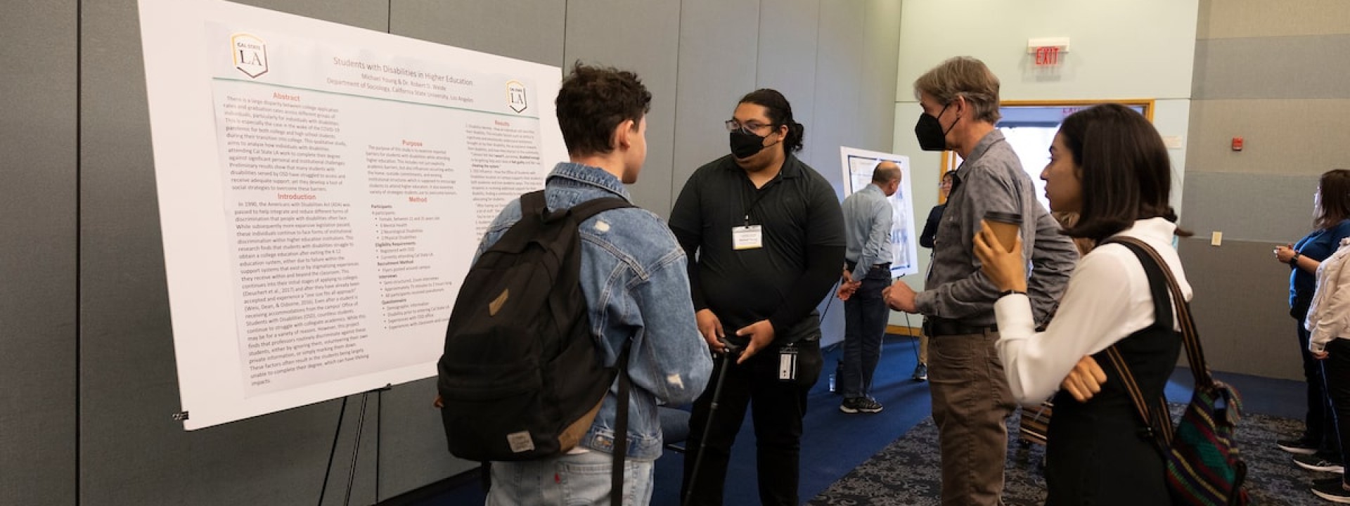 Student with cane presenting research poster to three listeners